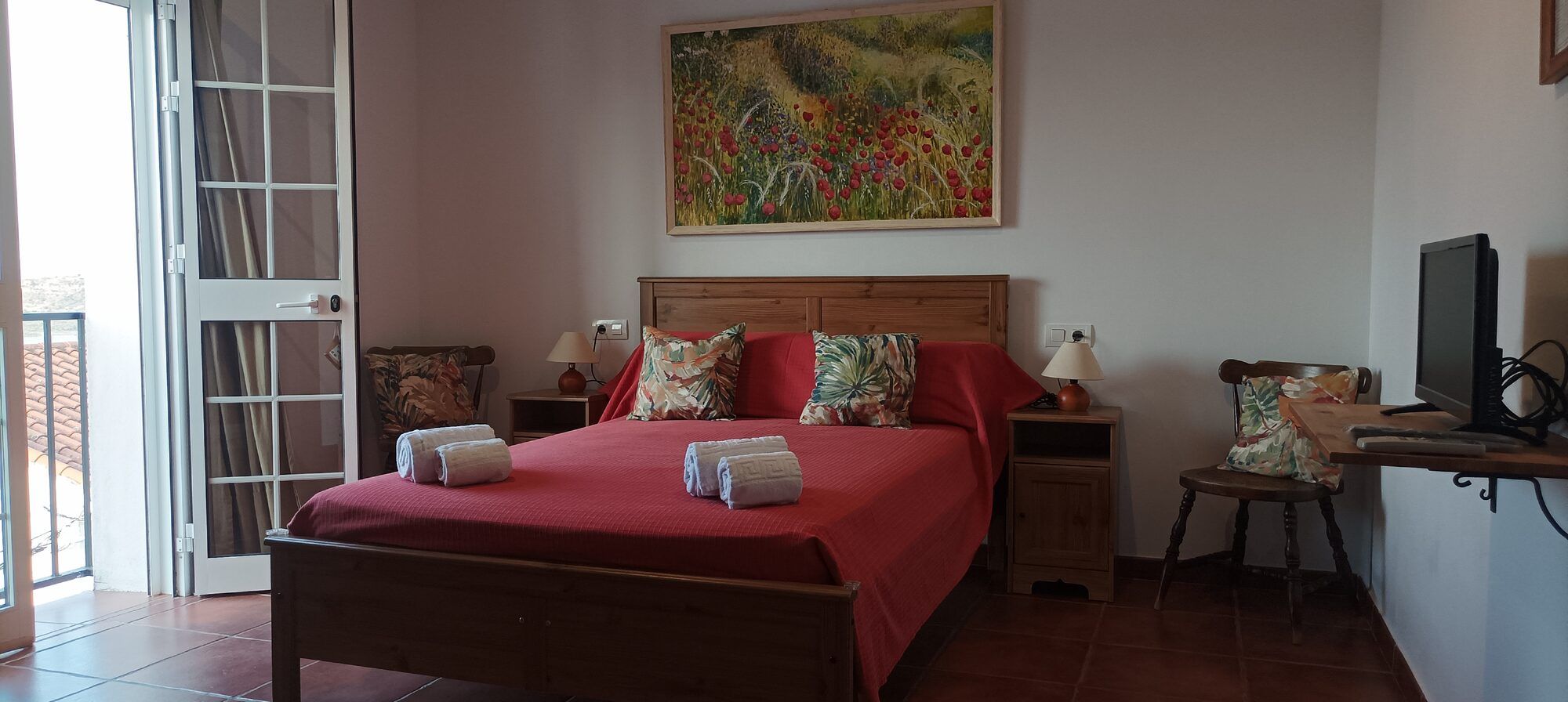 Cama junto al balcón de la habitación Amapola