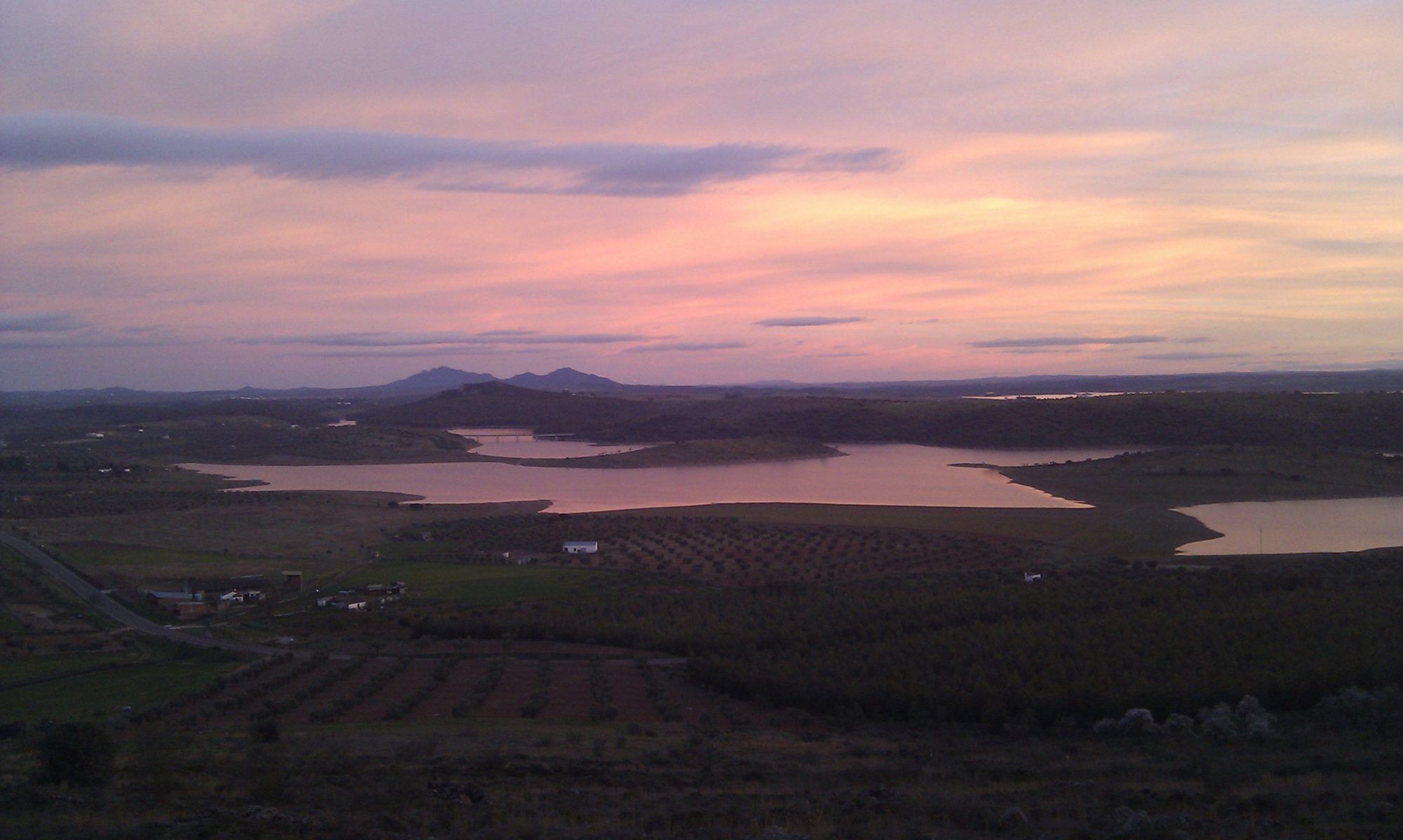 Atardecer rosado sobre el embalse y los olivares