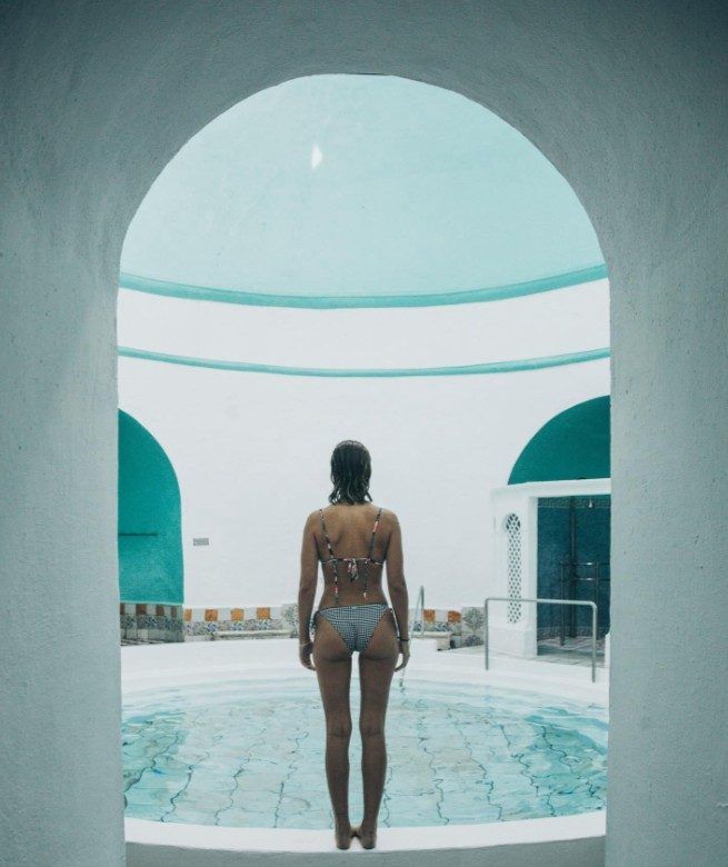 Bañista ante la piscina termal, bajo un arco