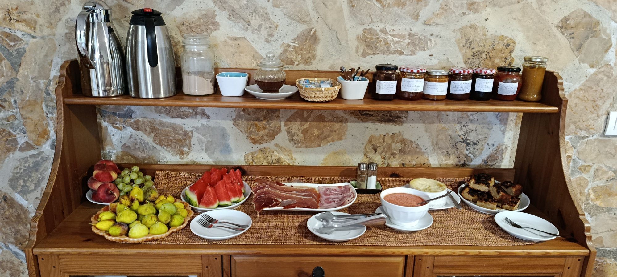 Aparador con el desayuno buffet preparado: fruta, embutido y mermeladas