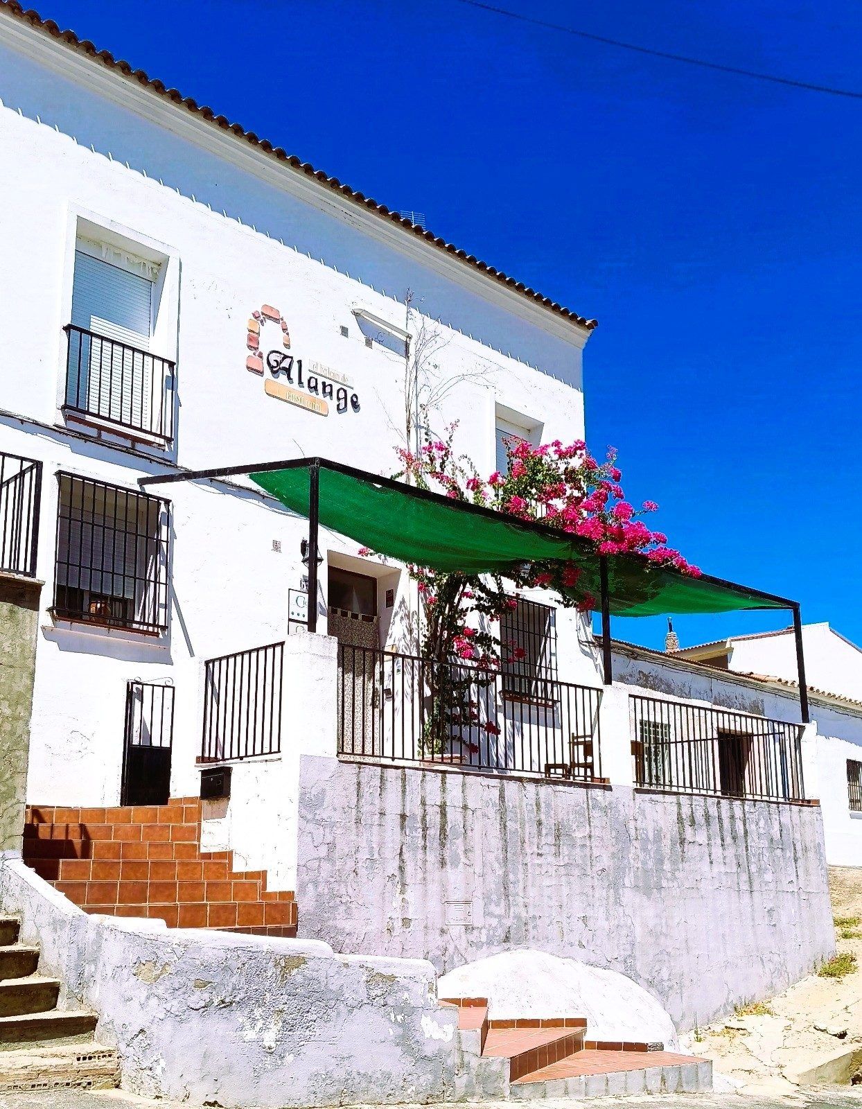 Fachada blanca y escalera de acceso a la casa
