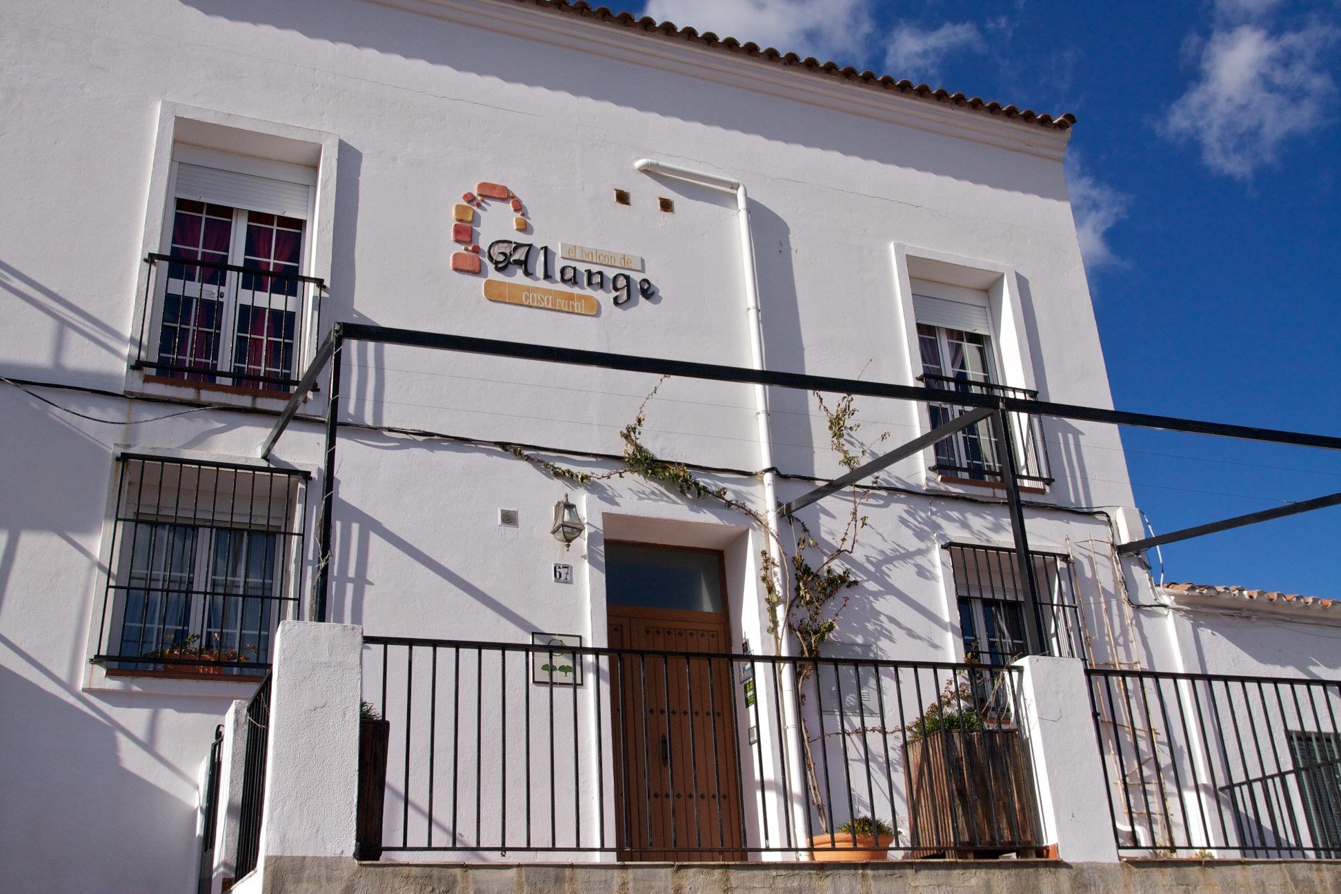 Fachada blanca del Balcón de Alange, con el rótulo y la puerta de entrada