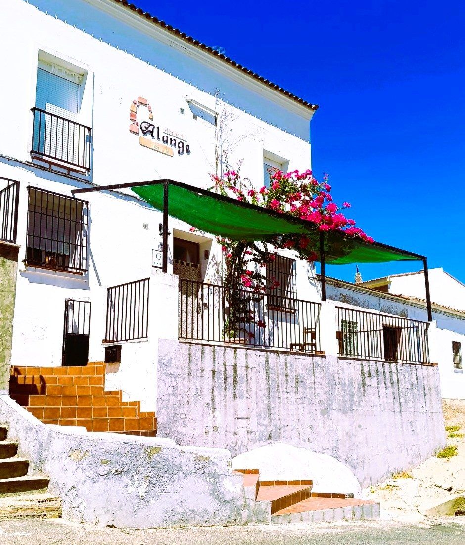 Fachada blanca y terraza bajo el toldo verde