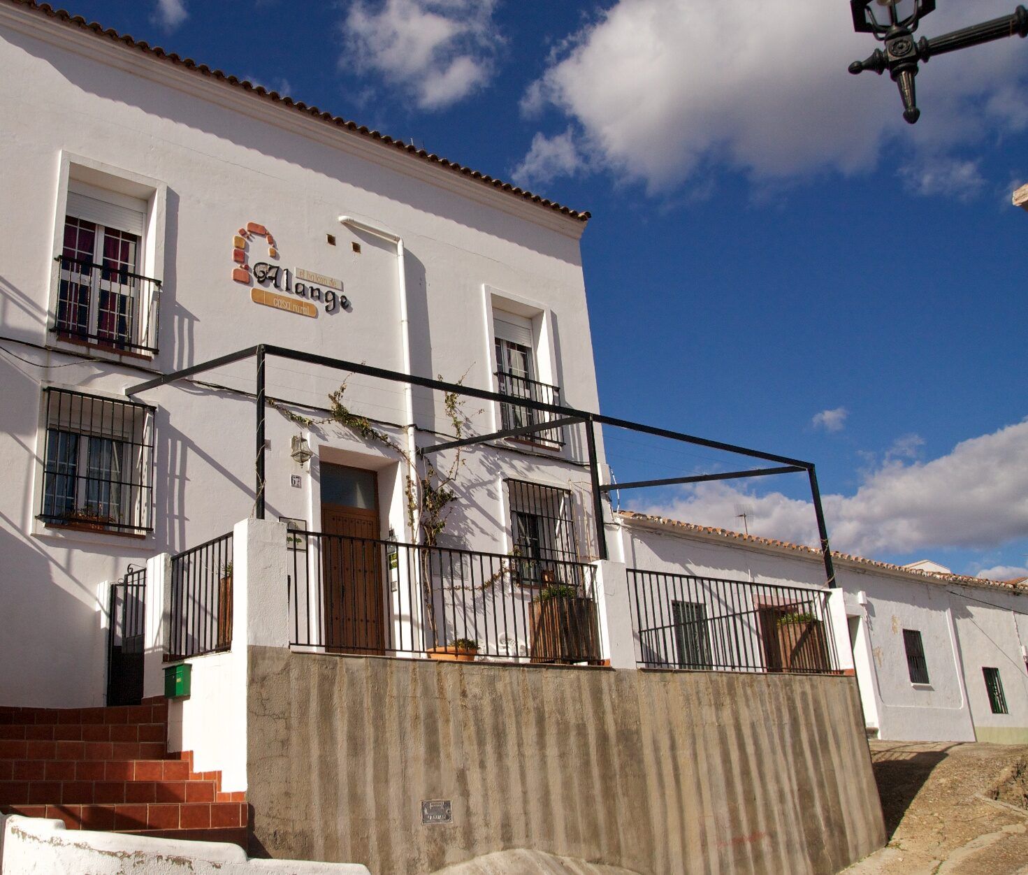 Fachada encalada del Balcón de Alange, con su rótulo y la escalera de acceso