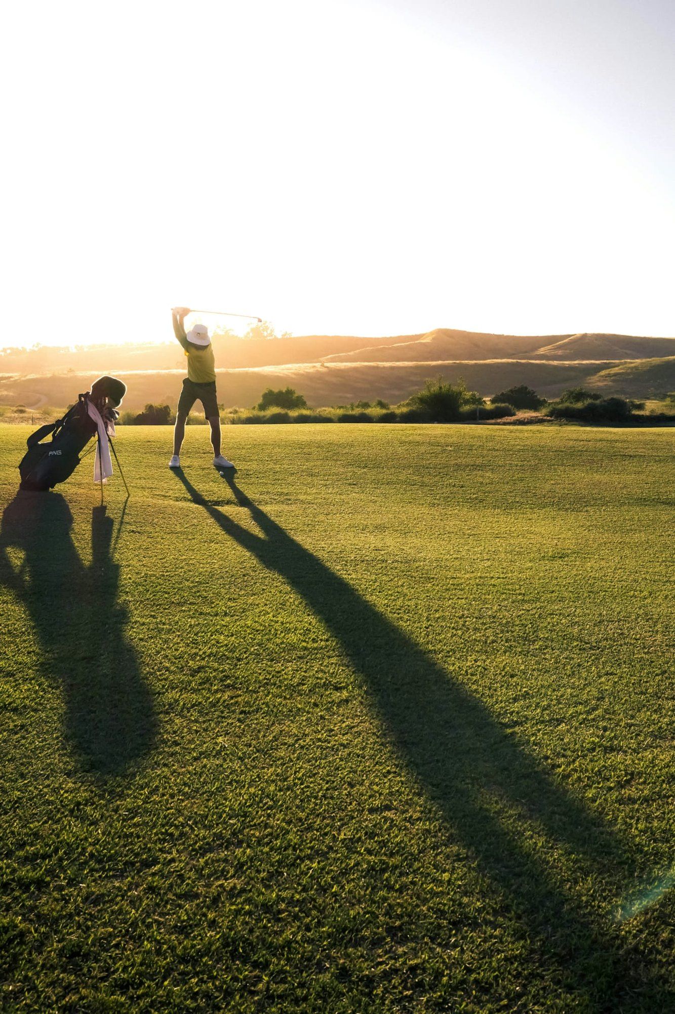 Una persona golpeando la bola en el campo de golf Don Tello, a contraluz del atardecer