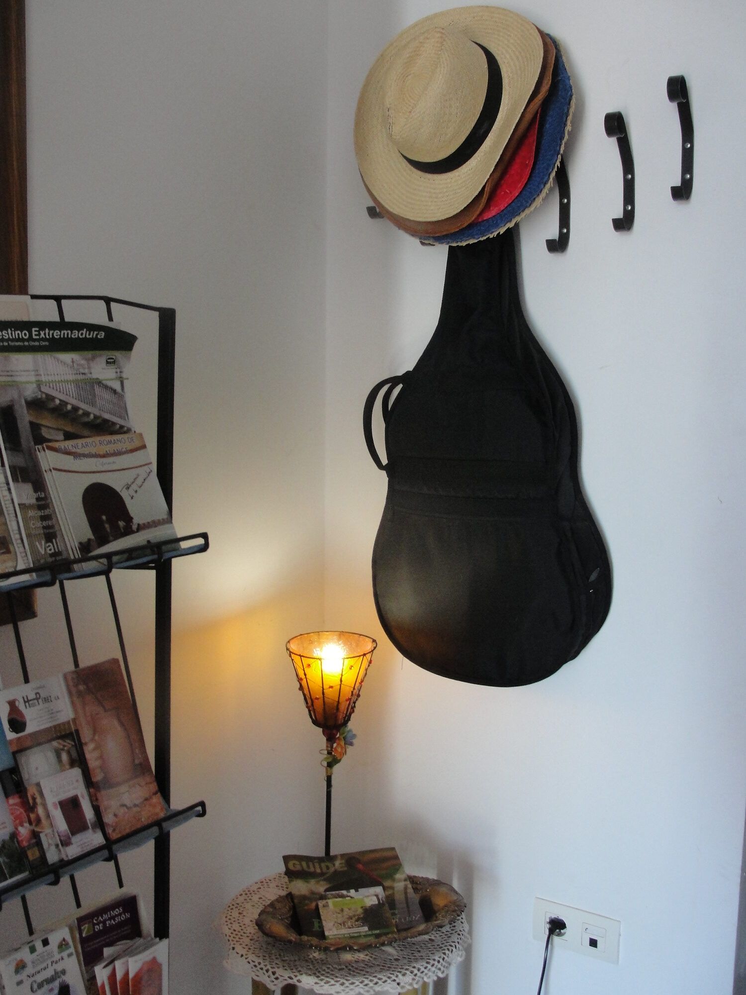 Rincón del salón con una guitarra colgada y una percha de sombreros