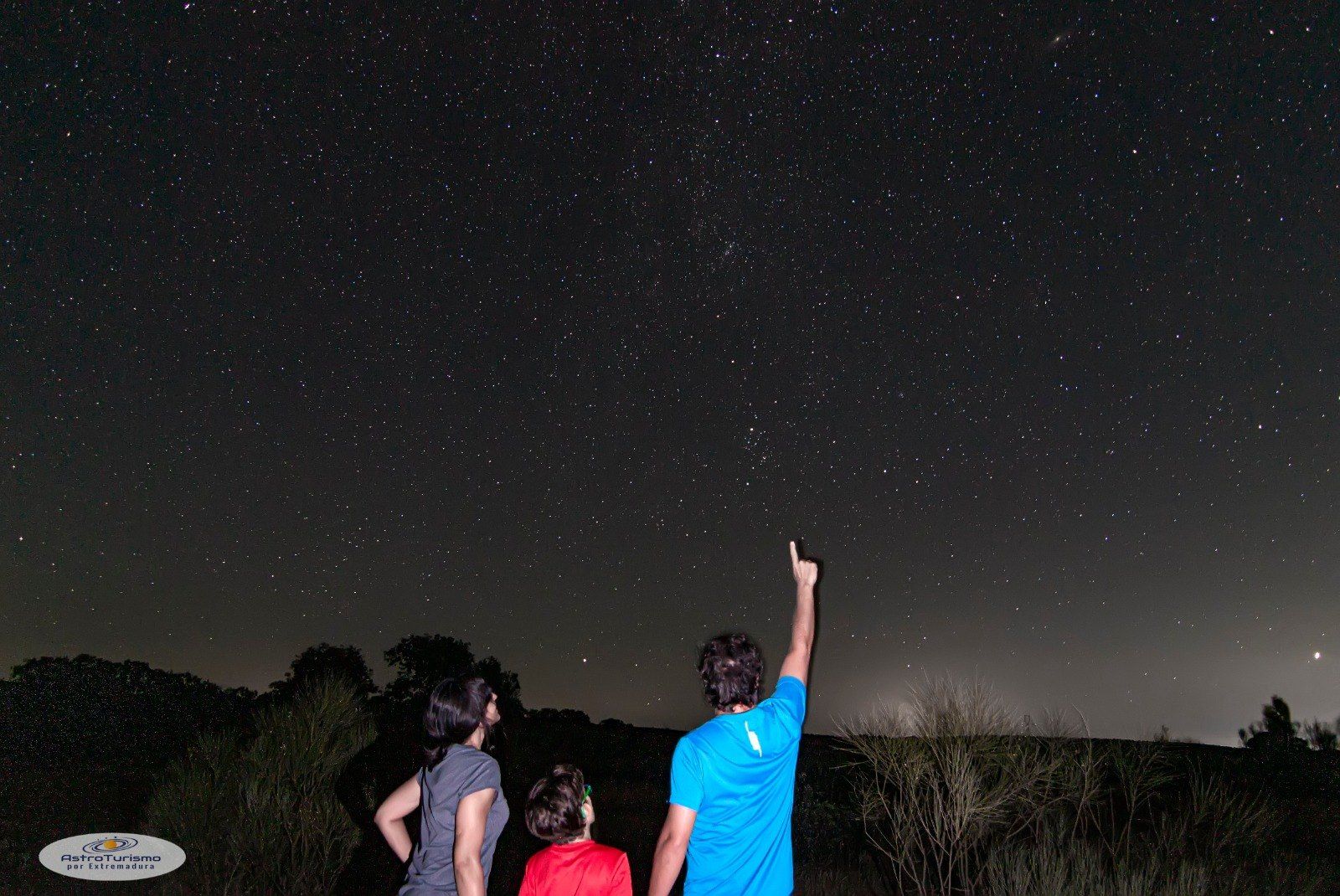 Una familia de noche en el campo, señalando las estrellas