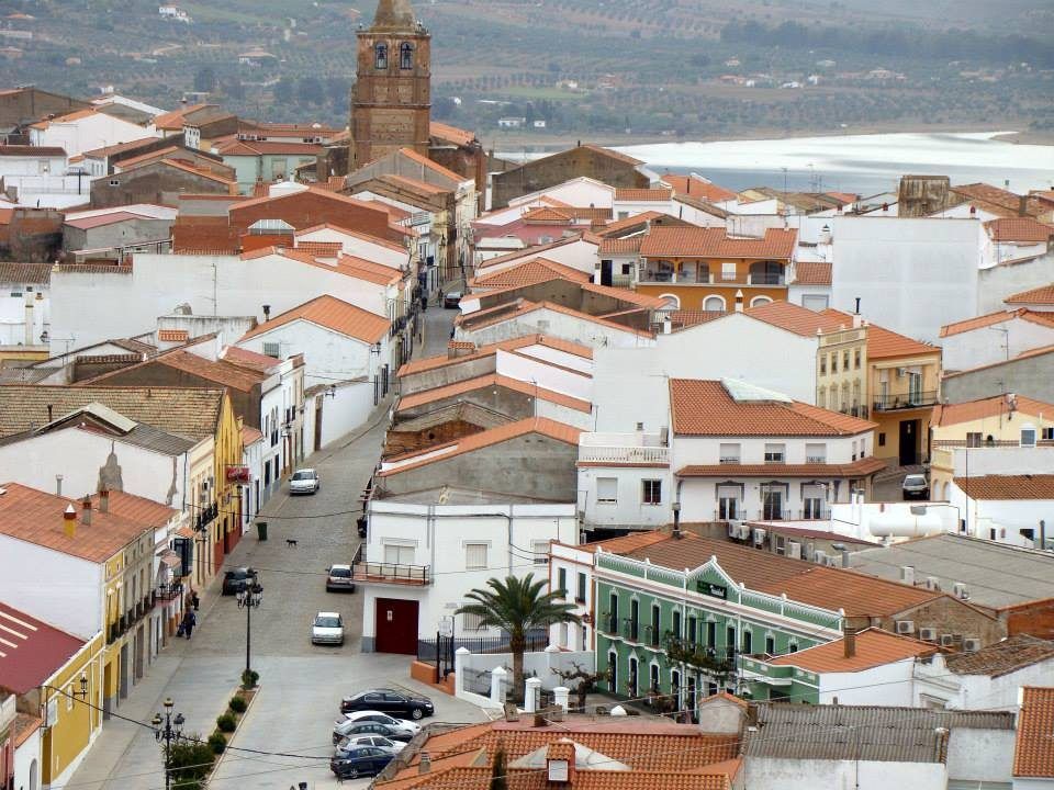Calles y tejados del pueblo, con la torre de la iglesia y el embalse al fondo
