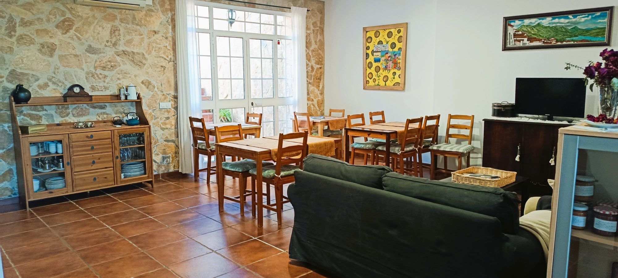 Salón-comedor con los sofás, las mesas del desayuno y la pared de piedra