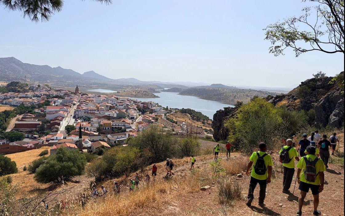 Grupo de senderistas por el camino del castillo, con Alange y el embalse abajo